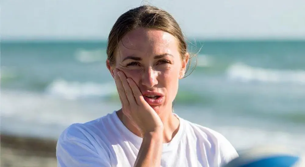 A girl holds her cheek after being hit by a volleyball